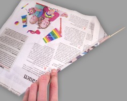 Holzspieß in Zeitungspapier einwickeln Bild vom Einwickeln eines Holzspießes in Zeitungspapier