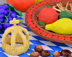 Erntedankkrone steht vor einem selbst gemachten Erntedankkorb. Traditionelle bayerische Handwerkskunst mit Herbstkastanien Bild von Erntedankfestfeier in Bayern: Erntedankkrone mit Früchten und Kastanien. Arrangiert von Veronika Vetter Bewahrerin des katholischen Glaubens