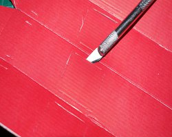 Bild von Wellpappe, welche mit einem Bastelmesser bearbeitet wird