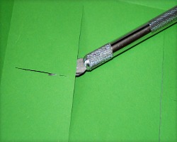 Einschneiden des Bodenelements Bild von Bastelmesser und grünem Tonpapier