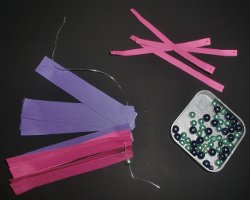 Bild von Papierstreifen die auf ein Nylonband aufgefädelt werden