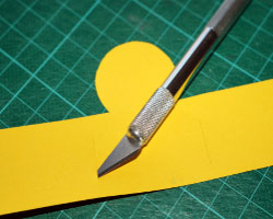 Element für Papierküken wird eingeschnitten Bild von Bastelmesser, welches ein Papierelement einschneidet