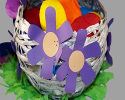 Bild vom lilafarbenen Papierblumen, die am Osternest kleben