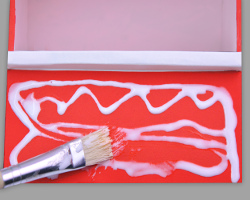 Wände mit weißem Bastelkleber bestreichen, um Holzoptik zu erzeugen Bild vom Bestreichen der roten Papierwände mit weißem Bastelkleber, um Holzoptik zu erzeugen