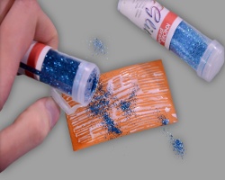 Blauer Glitter rieselt auf Fensterelement Bild vom blauen Glitter, der auf ein Fensterelement mit Kleber rieselt