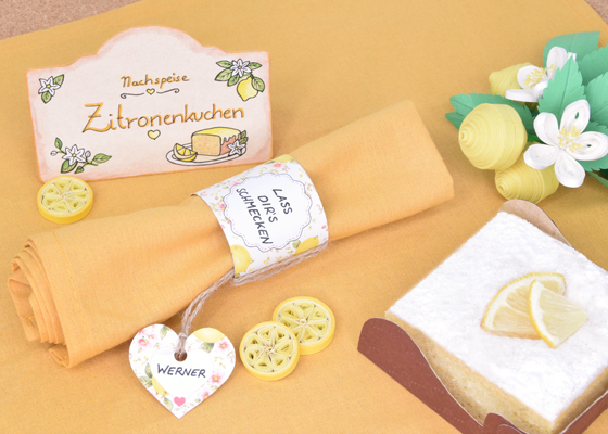 Handgefertigter Serviettenring im Zitronendesign mit Namensschild, Quilling-Dekoration und selbst gebackenem Zitronenkuchen für eine sommerliche Tischdekoration. Veronika Helga Vetter - Linz Österreich - Papierkünstlerin Im Mittelpunkt dieser liebevoll gestalteten Tischdekoration steht ein handgefertigter Serviettenring im frischen Zitronendesign, der einer einfachen Stoffserviette im Handumdrehen eine persönliche und sommerliche Note verleiht. Die in warmem Pastellgelb gehaltene Serviette wurde sorgfältig zusammengerollt und von einem dekorativen Papierband umschlossen, das mit kleinen Zitronen, Blüten und einer freundlichen Grußbotschaft verziert ist. Ergänzt wird der Serviettenring durch ein herzförmiges Namensschild, das mit einer rustikalen Jute-Schnur befestigt wurde. Diese Kombination aus natürlichen Materialien und fröhlichen Farben sorgt für eine einladende Atmosphäre und macht jeden Gast bereits beim Betreten der festlich gedeckten Tafel willkommen. Die gesamte Dekoration greift das beliebte Zitronenthema auf, das seit einigen Jahren zu den gefragtesten Sommertrends im deutschsprachigen Raum gehört. Direkt hinter dem Serviettenring befindet sich eine passende Platzkarte mit der Aufschrift „Nachspeise – Zitronenkuchen“, die das Motiv stilvoll fortsetzt. Rechts unten im Bild ist ein selbst gebackener Zitronenkuchen zu sehen, dessen zarte Puderzuckerschicht und frische Zitronengarnitur perfekt mit der übrigen Dekoration harmonieren. Anders als bei vielen Produktfotos handelt es sich hierbei nicht um ein gekauftes Schauobjekt, sondern um einen echten, selbst gebackenen Kuchen, der von Veronika Helga Vetter eigens für dieses Arrangement zubereitet wurde. Besondere Aufmerksamkeit verdienen auch die zahlreichen kleinen Dekorationselemente, die auf den ersten Blick leicht übersehen werden können. Die Zitronenscheiben im Vordergrund sowie die kunstvollen Zitronenblüten rechts oben wurden in der Quilling-Technik gefertigt. Bei dieser kreativen Papierkunst werden schmale Papierstreifen zu filigranen Formen gerollt und anschließend zu dekorativen Motiven zusammengesetzt. Die detailreichen Quilling-Arbeiten verleihen dem Bild eine außergewöhnliche Tiefe und unterstreichen den handgemachten Charakter der gesamten Szene. Jedes einzelne Element dieser sommerlichen Tischdekoration wurde von Veronika Helga Vetter selbst entworfen, gebastelt, arrangiert und fotografiert. Das Ergebnis zeigt eindrucksvoll, wie sich mit wenig Aufwand und viel Liebe zum Detail eine festliche Tischgestaltung für Gartenpartys, Familienfeiern, Geburtstage, Kaffeerunden oder sommerliche Nachmittage auf der Terrasse verwirklichen lässt. Die abgebildeten Serviettenringe können übrigens ganz einfach nachgebastelt werden. Die dafür benötigten Vorlagen und Schablonen stehen kostenlos auf GWS2.de zum Download bereit und lassen sich vor dem Ausdrucken sogar individuell mit Namen oder persönlichen Grußbotschaften beschriften. Juni 2026