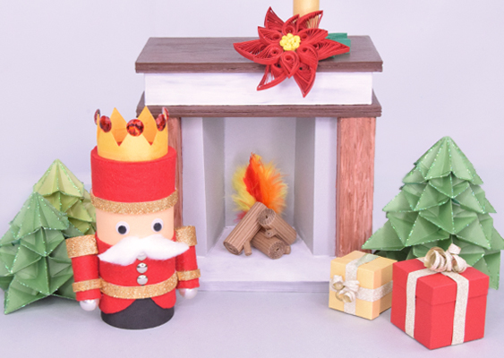 Nussknacker im roten Königskostüm vor Origami-Tannen und einem detailreichen Papierkamin mit Quilling-Weihnachtsstern und Geschenken – winterliche DIY-Szene von Veronika Helga Vetter Die Szene zeigt ein liebevoll inszeniertes Winterarrangement, das auf den ersten Blick wie ein kleiner Ausschnitt aus einem märchenhaften Weihnachtsdorf wirkt. Im linken Vordergrund steht der stolze Papier-Nussknacker, dessen Erscheinung unübersehbar an den legendären „Roten König“ aus dem erzgebirgischen Seiffen erinnert. Seine kräftig rote Uniform wurde mit goldenen Bordüren geschmückt, die im Licht feierlich aufscheinen. Über seinem Kopf thront eine ebenfalls rote Krone, die mit kleinen Schmucksteinen besetzt ist und der Figur eine beinahe königliche Würde verleiht. Die Wackelaugen blicken wach und aufmerksam in die Szene, während ein weicher, weißer Schnauzbart aus Watte dem strengen Offizierscharakter eine charmante, fast schelmische Note verleiht. Der Hintergrund ist in schlichtem Weiß gehalten, wodurch der Eindruck einer verschneiten Winterlandschaft entsteht. Hinter dem Nussknacker stehen zwei Origami-Weihnachtsbäume in unterschiedlichen Grüntönen. Ihre kunstvoll gefalteten Schichten sind mit grünem Glitzer bestäubt, sodass die Bäume im Licht aufblitzen wie vereister Tannenschmuck – dezent, aber wirkungsvoll. Zur Rechten des Nussknackers befindet sich das eigentliche Highlight der Szenerie: ein Kamin, vollständig aus Papier gefertigt, jedoch so detailreich nachgebildet, dass man fast meint, es handle sich um ein echtes Miniaturmodell. Die Oberfläche des Kamins zeigt holzartige Marmorstrukturen, die den Eindruck eines edlen, schweren Möbels vermitteln. Im Kamininneren liegen gerollte Wellpapp-Scheite, die in ihrer Textur fast wie echtes Brennholz wirken. Zwischen ihnen lodert ein „Feuer“, dargestellt durch weiche, fächerartig arrangierte Federn in Rot, Orange und Gelb, die eine warme, lebendige Flammenoptik erzeugen. Auf der Kaminsimse ruht ein aus Quilling gearbeiteter Weihnachtsstern: zarte Papierstreifen, kunstvoll gerollt, bilden rote Blütenblätter und grüne Blätter, dahinter steht eine kleine Papierkerze, die das Ensemble abrundet. Diese feine Papierarbeit verleiht der Szenerie eine zusätzliche Ebene von filigraner Eleganz. Im rechten Vordergrund stehen zwei kleine Geschenke aus Papier, sorgfältig als klassische Geschenkverpackungen gestaltet – eines in Vanille, eines in Rot. Sie wirken wie frisch unter den Weihnachtsbaum gelegt und verleihen der Szene ein Gefühl von Vorfreude und behaglicher Festlichkeit. Die gesamte winterliche Nussknackerlandschaft wurde von Veronika Helga Vetter entworfen, gebastelt, inszeniert und fotografiert – ein detailreiches DIY-Kunstwerk und ein liebevoller Lifehack zum Nachbasteln für GWS2.de. Dezember 2025