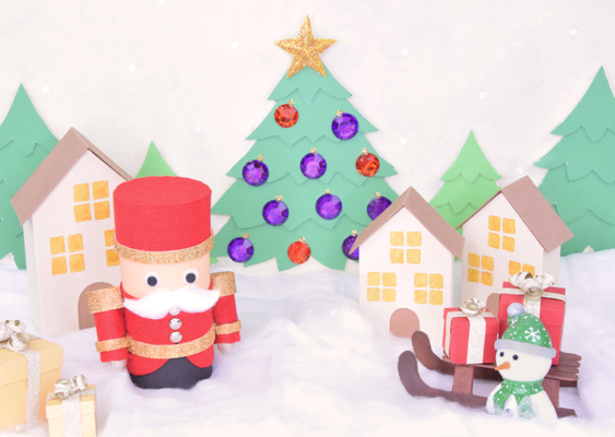 Winterliches Papierdorf mit rotem Nussknacker, geschmücktem Weihnachtsbaum, Papierhäusern, Geschenken, Schneemann und Schlitten – DIY-Szene von Veronika Helga Vetter Die Szene wirkt wie ein friedliches, kleines Winterdorf, das gerade inmitten einer sanften Schneelandschaft erwacht ist. Im Zentrum steht ein Nussknacker aus Papier, festlich herausgeputzt in einem strahlend roten Gewand. Sein breiter Zylinder, die goldenen Bordüren und die kleinen, präzise platzierten Knöpfe verleihen ihm das würdige Auftreten eines festlichen Torwächters, der über das Weihnachtsdorf wacht. Der weiße Wattebart ist üppig und weich geformt, und die großen Wackelaugen verleihen der Figur einen warmherzigen, beinahe wachtmeisterlichen Ausdruck. Hinter dem Nussknacker reihen sich mehrere Papierhäuser, deren Fassaden in zartem Vanilleton gehalten sind. Die Fenster sind in warmem Gelb hinterlegt, sodass es wirkt, als würden im Inneren Kerzen brennen oder ein Kachelofen leise glühen. Die Häuser unterscheiden sich leicht in Größe und Dachform, bilden aber gemeinsam eine harmonische Dorfkulisse, die ideal in diese winterliche Szenerie passt. Im Hintergrund erhebt sich ein Weihnachtsbaum aus mehreren grünen Papierlagen, die wie übereinandergelegte Zweigschichten wirken. Der Baum ist mit einer Vielzahl farbkräftiger Schmucksteine verziert: violette, rote und orangefarbene Ornamente glitzern im Licht, als würden sie von einem unsichtbaren Kaminfeuer beleuchtet. An der Spitze thront ein goldener Stern, der über die gesamte Szenerie einen festlichen Glanz legt. Rechts und links daneben stehen weitere kleinere Bäume in einem etwas dunkleren Grünton, wodurch die Komposition Tiefe erhält und das Gefühl eines ruhigen Waldrandes entsteht. Im Vordergrund breitet sich eine weiche Schneedecke aus, dargestellt durch watteartige, unregelmäßige weiße Polster. Auf dieser Schneefläche stehen mehrere kleine Geschenke in Gold- und Vanilletönen, sorgfältig mit glänzenden Schleifen verziert – als hätte der Weihnachtsmann gerade erst seine Lieferung begonnen. Rechts im Bild entdeckt man außerdem einen kleinen Schlitten, auf dem sich mehrere rot-weiße Päckchen stapeln. Daneben steht ein Schneemann aus Papier, mit grünem Schal und passender Mütze. Seine runde Statur und sein freundliches Gesicht fügen der Szenerie eine kindliche Freude hinzu, wie man sie aus alten Weihnachtsbüchern kennt. Der Schlitten wirkt so, als würde er gleich losziehen, um die Geschenke durch das Dorf zu verteilen. Die gesamte Komposition wirkt liebevoll, ruhig und gleichzeitig wunderbar lebendig – ein winterliches Diorama, das das Gefühl eines weihnachtlichen Dorfes in Papierform einfängt. Gestaltet, gebastelt und fotografiert wurde diese Szene von Veronika Helga Vetter, Papierkünstlerin, Photoshop-Meisterin und kreative Erzählerin von GWS2.de